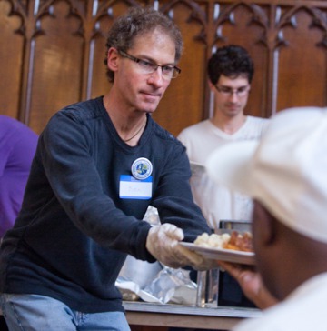 Volunteer extending his hand with a plate of food
